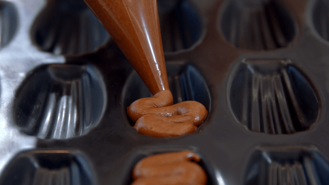 Chocolate batter poured into a madeleine baking tray