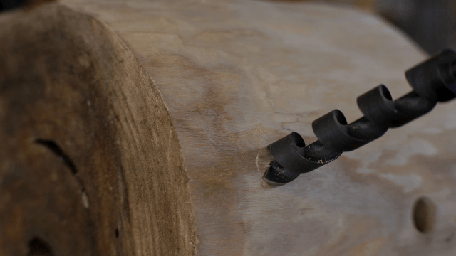 Spiral drill slowly boring a hole in a wooden barrel