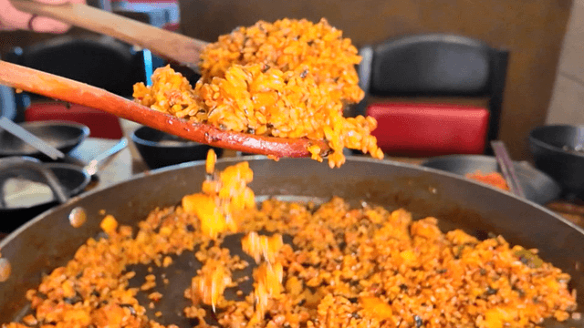 Glossy fried rice falling from spatula on iron plate