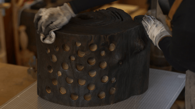 Artisan wiping a charred wooden piece with a cloth