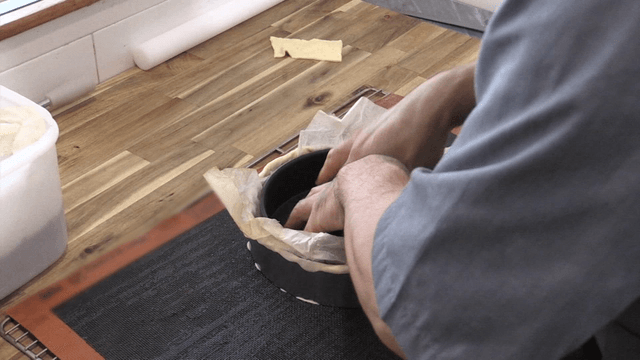 조리대 위에서 베이킹 틀에 반죽을 준비하는 제빵사