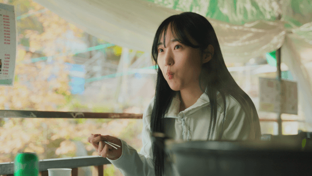 Young woman eating white chicken soup at forest lodge