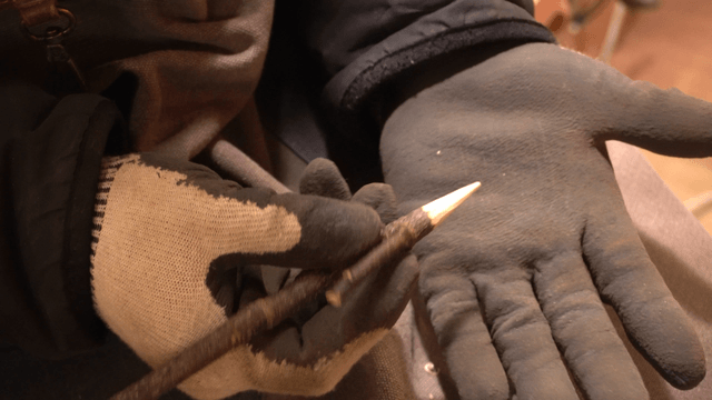 Gloved hand holding pencil-shaped wood