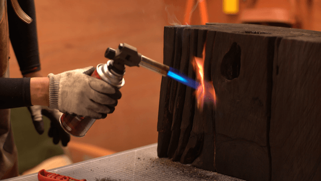 Artisan burning and brushing wood in workshop