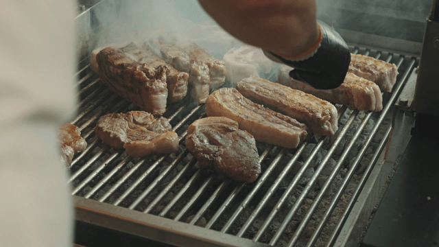 Grilling meat on a barbecue with smoke
