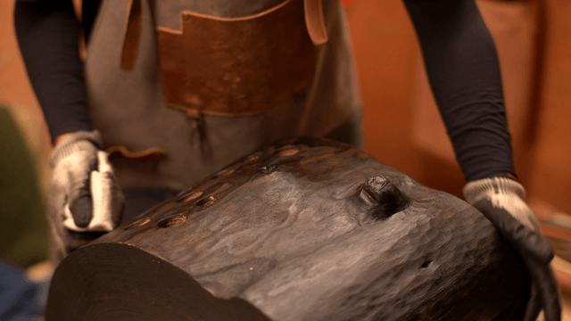Woodcraft artisan polishing a wooden sculpture with a cloth