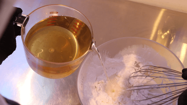 Pouring liquid into a bowl with flour
