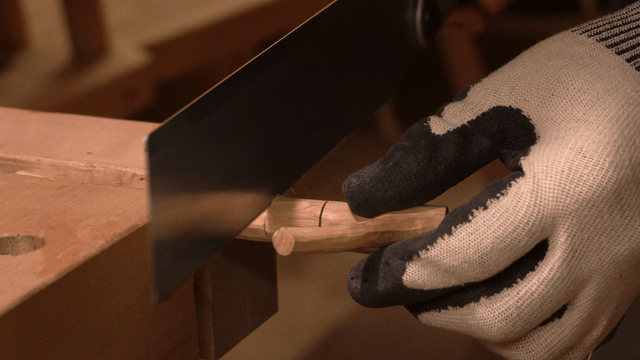 Woodcraft artisan cutting wood with a saw in workshop