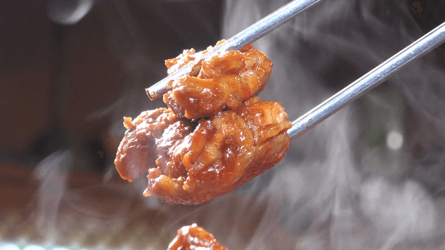 Grilled stir-fried chicken meat held with chopsticks