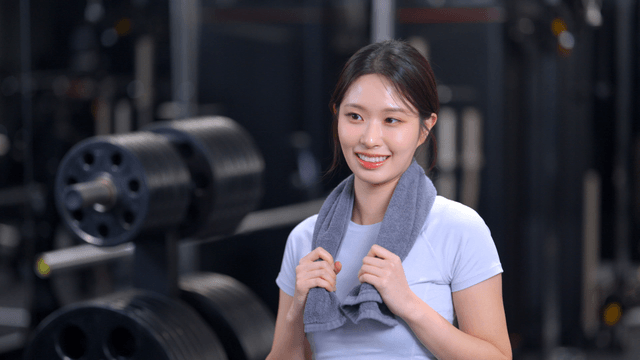 Profile of young woman smiling with a towel in a gym