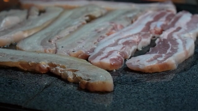 Pork belly grilling on a hot stone