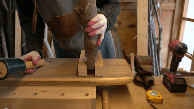 Woodcraft artisan using a rubber mallet on wood in workshop