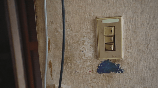 Old broken light switch on a worn wall