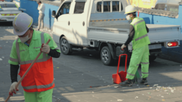 Street cleaners working near parked vehicles
