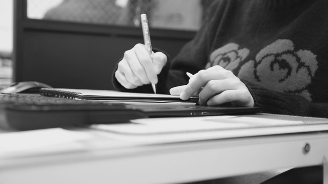 A person writing notes at a desk