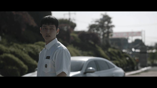 Male student looking back in front of car