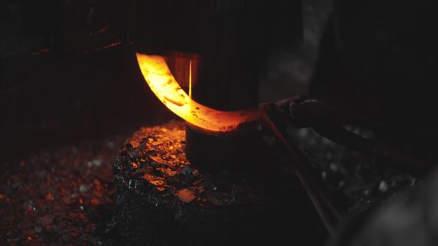 Hot metal being forged by machine in workshop