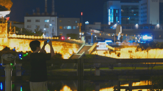 Night view capturing a traditional fortress by a man with a phone