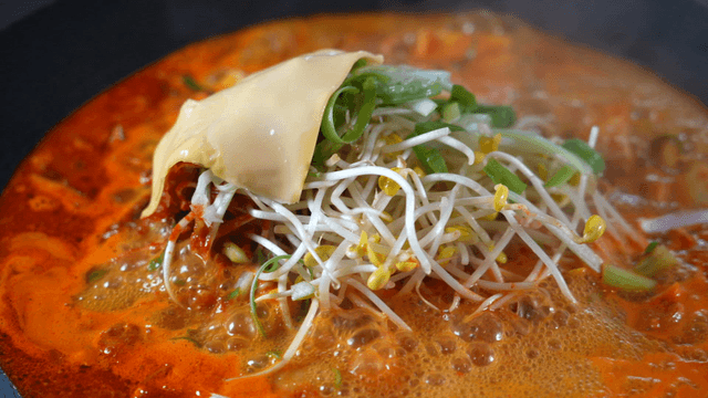 Boiling budaejjigae topped with cheese and bean sprouts