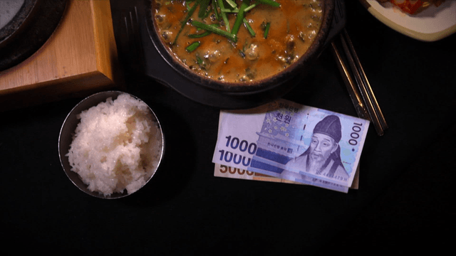 Korean banknotes placed beside hot stone pot rice and loach soup