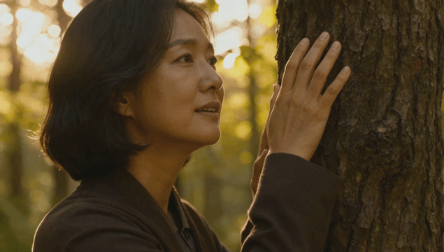 숲속에서 거친 나무줄기를 만지고 웃음짓는 여성