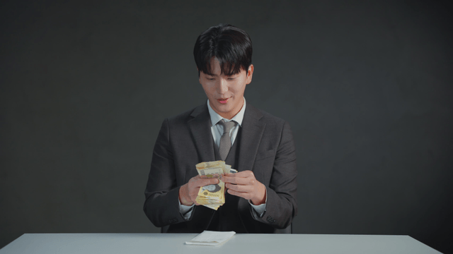 Man in a suit counting money at a table