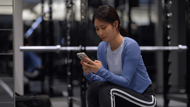 Young woman using smartphone in a gym
