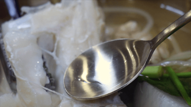 Tongs holding cod soup fillet