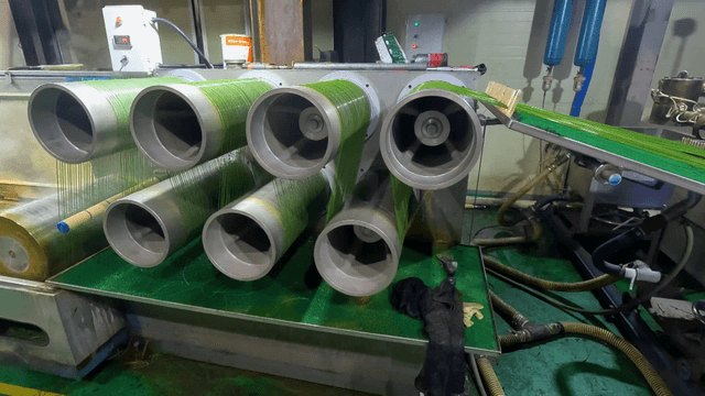 Green threads winding around rotating factory machines