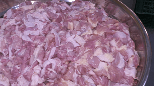 Raw chicken pieces in a large metal bowl
