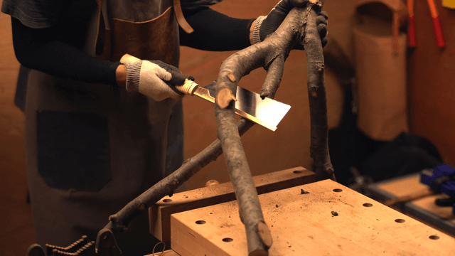 Craftsman cutting wood branches indoors