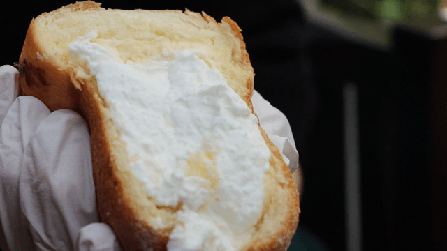 Cream-filled pastry held in gloved hand