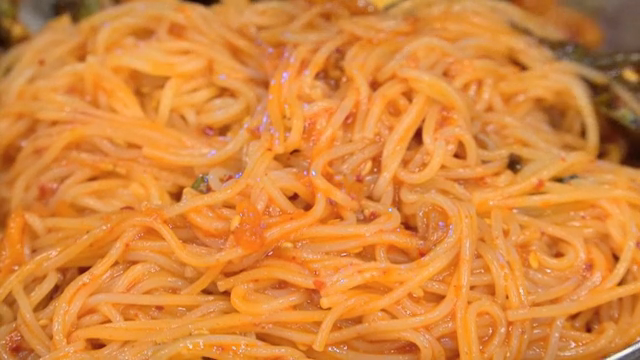 Spicy noodles being mixed in a bowl
