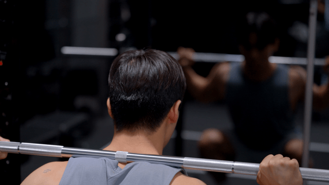 Man performing squat with weighted bar on shoulders