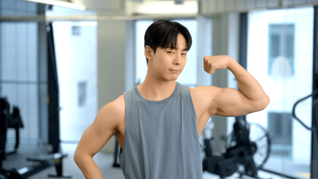 Young man showing arm muscles at gym