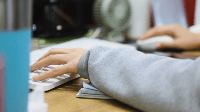 Hands typing on a keyboard in an office