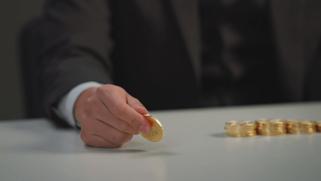 A person holding a bitcoin at a table