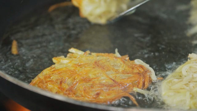 Golden potato pancakes frying in a pan