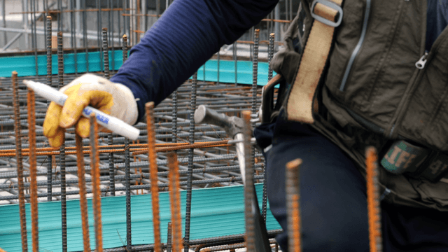 Worker marking steel bars at a construction site