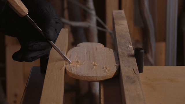 Hands carving wood with a chisel in workshop