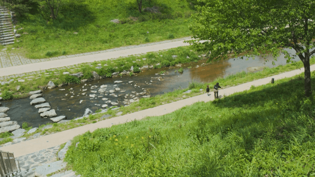 Child and mother walking along the riverside on a clear day
