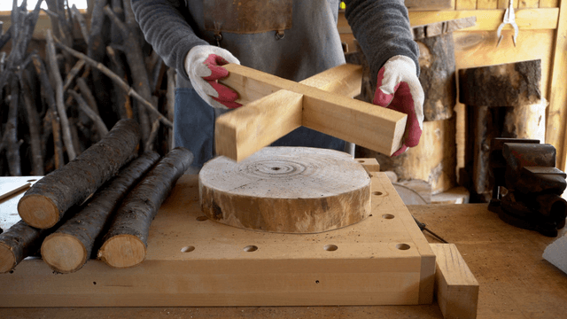 Woodworker examining logs and wooden materials in workshop