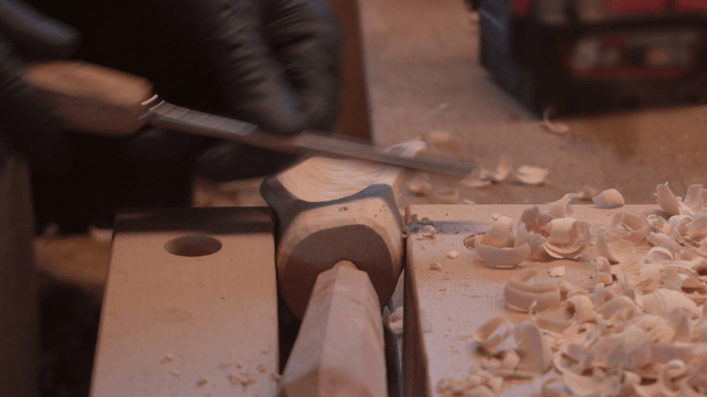 Wooden scoop being carved with a chisel