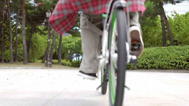 Person cycling through a park path