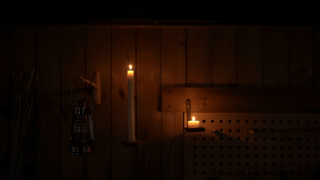Candle lit against a dark wooden wall