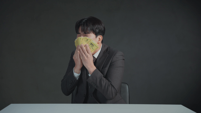 Man smelling money with a satisfied expression