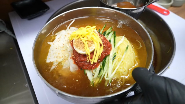 Korean Cold Buckwheat Noodles with broth being served
