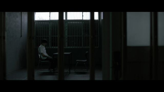 Person sitting alone in dark room with bars