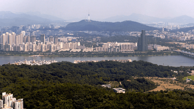 A city skyline with a river and mountains