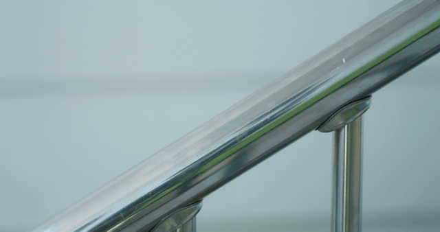 Hand holding a metal railing indoors